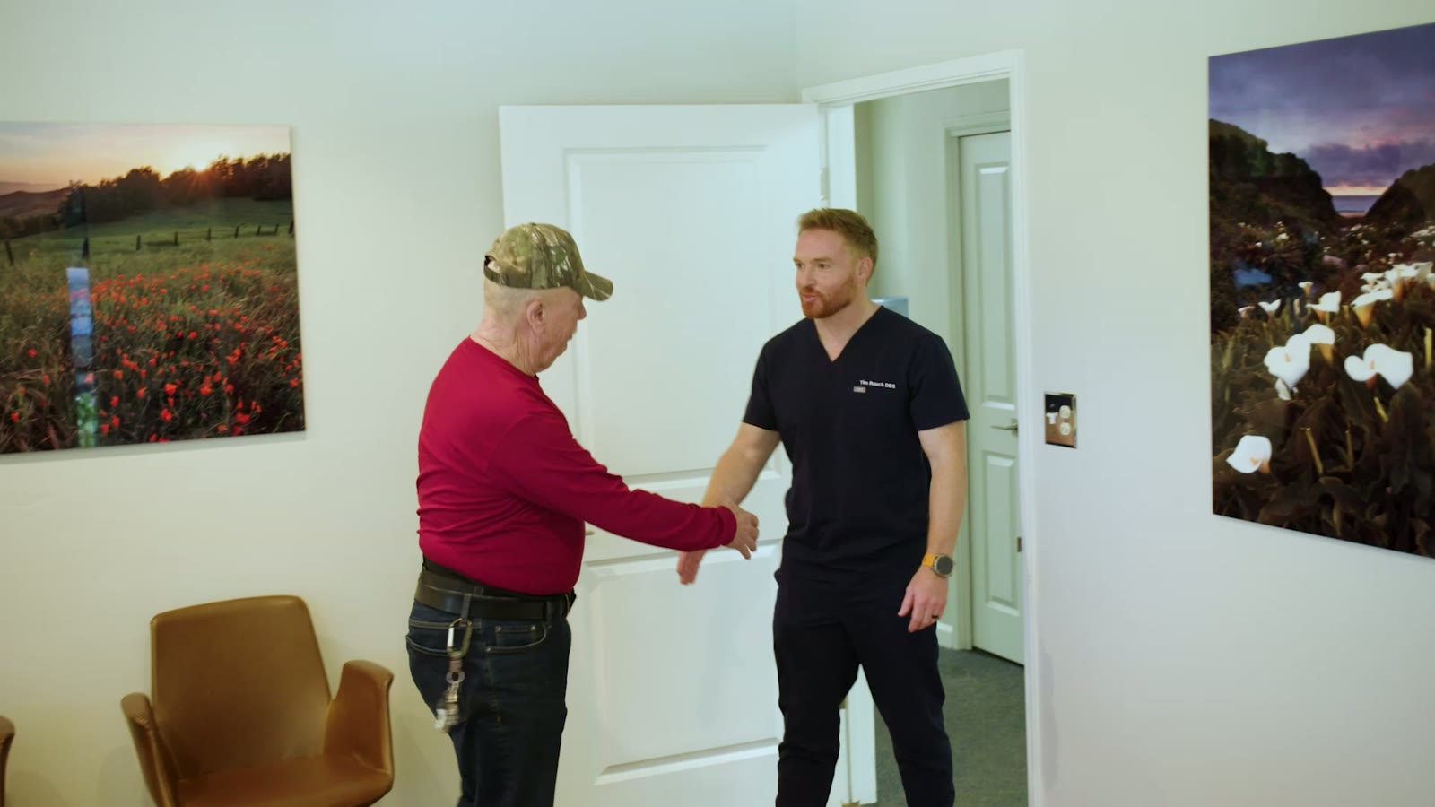 Dr. Rauch greeting a returning patient at the practice door, with the practice's poppy field art on the wall
